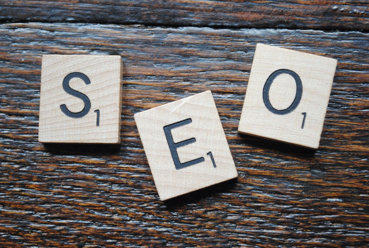 The Art of Drawing Readers In: Your attractive post title goes here Close-up of Scrabble tiles spelling SEO on a wooden table for content strategy.