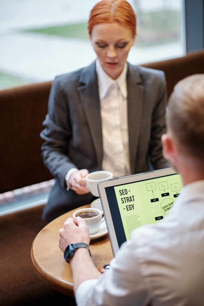 Mastering the First Impression: Your intriguing post title goes here Professional meeting in a café with a laptop showcasing an SEO strategy. Ideal for business concepts.